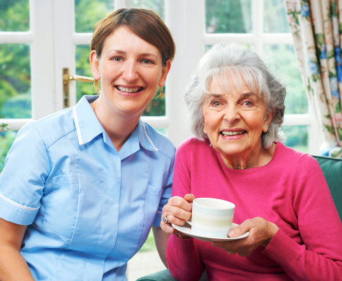 portrait of happy nurse and elderly woman holding a mug