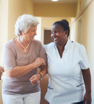 portrait of happy caregiver assisting elderly woman