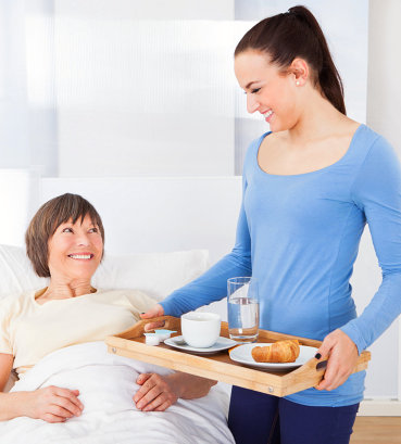 caregiver serving food to his patient in bed